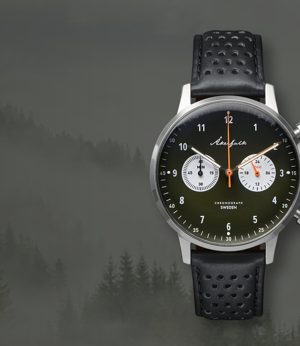 A wristwatch with a black perforated leather strap, a silver-toned round case, and a dark olive-green dial with white subdials and an orange second hand. From Akerfalk watches