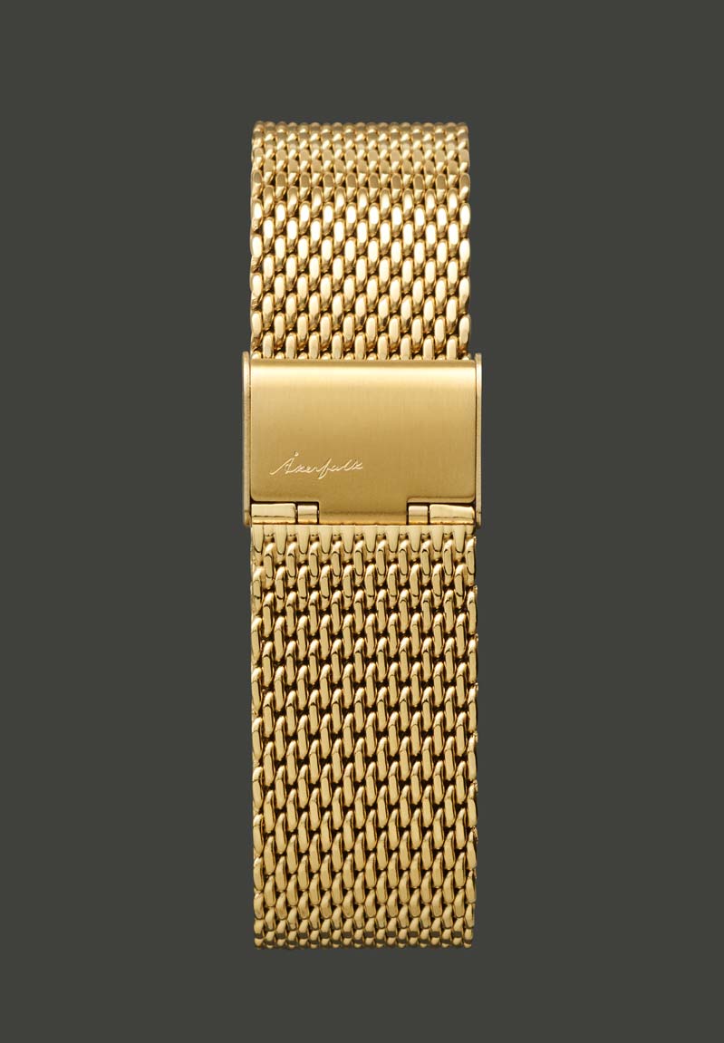 A gold-colored metal mesh watch strap with a buckle, viewed from the back.